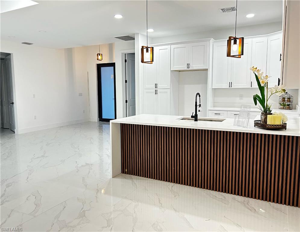 Modern kitchen island featuring a slatted wood-tone panel and a white countertop with an integrated sink