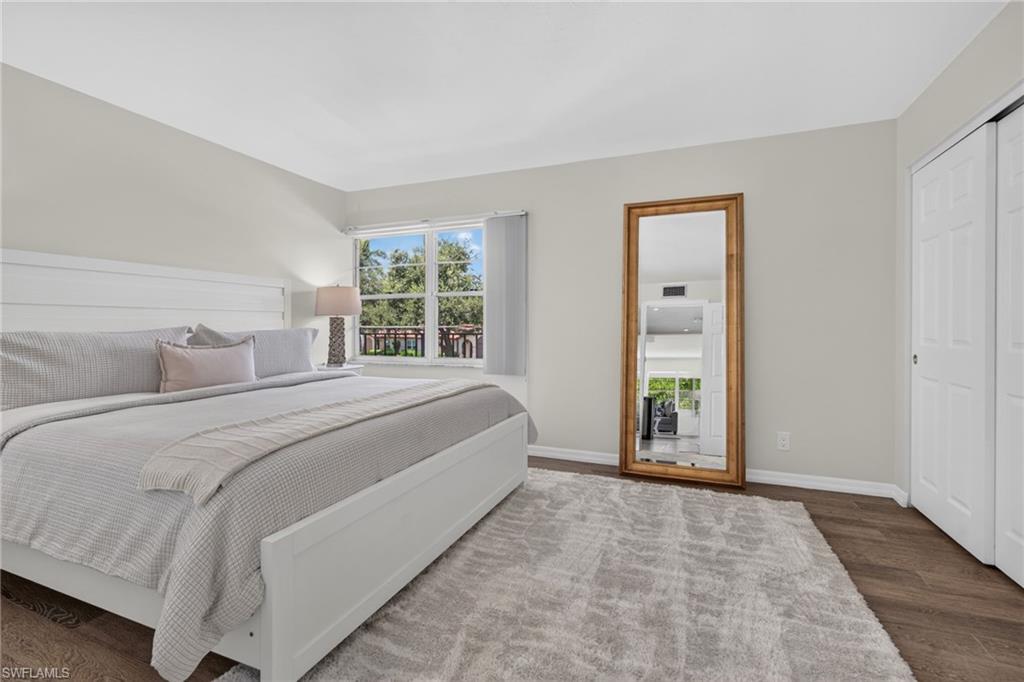 Spacious room featuring a wide window, wood-finish flooring, and white bifold closet doors