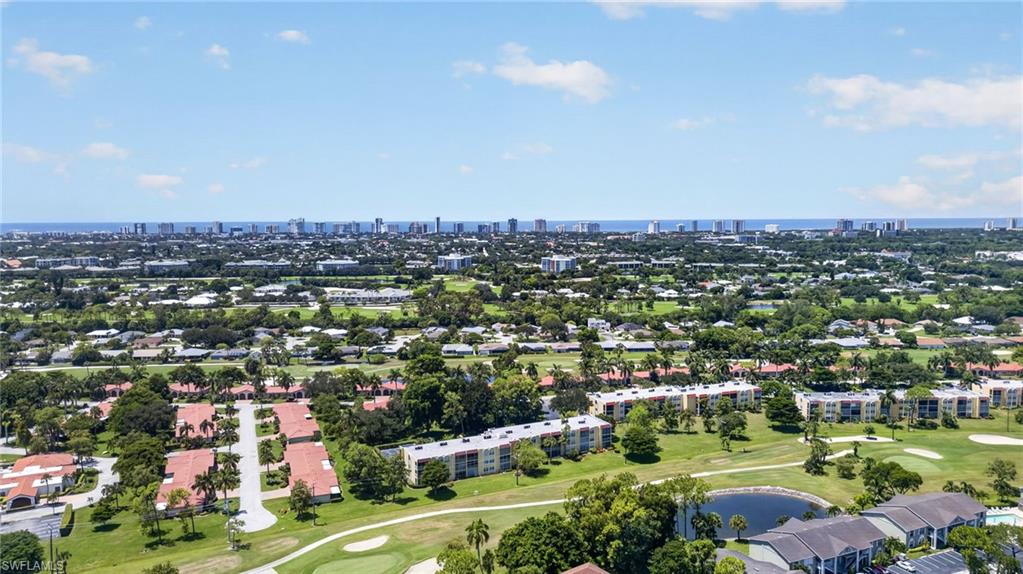 Expansive aerial perspective showcasing a golf course, residential structures, and a prominent distant skyline