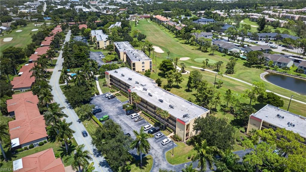 Extensive golf course frontage, multiple residential buildings, paved parking areas, mature landscaping, and a water feature
