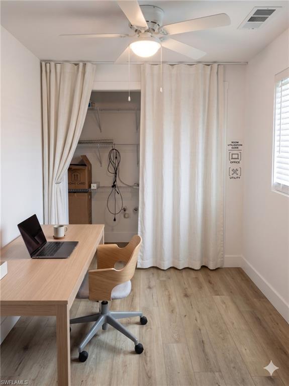 Room featuring wood-finish flooring, a ceiling fan with integrated lighting, and a window with horizontal blinds