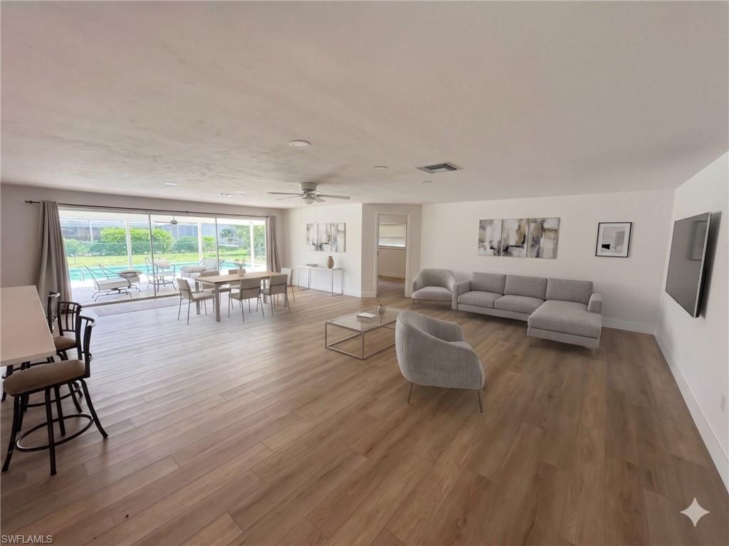 Open-concept living space featuring wood-finish flooring, white walls, and a recessed ceiling light
