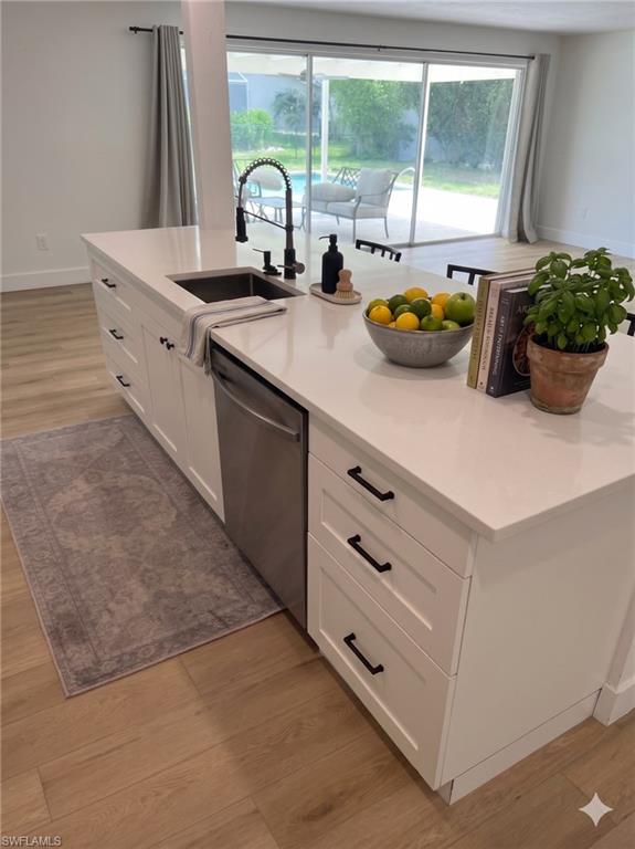 Kitchen island featuring a single-basin sink with a matte black gooseneck faucet, white shaker cabinetry with black hardware, and an integrated stainless steel dishwasher