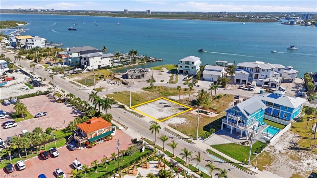 Cleared lot with direct road frontage, surrounded by residential properties and commercial establishments, offering proximity to open water - Virtually Edited Image