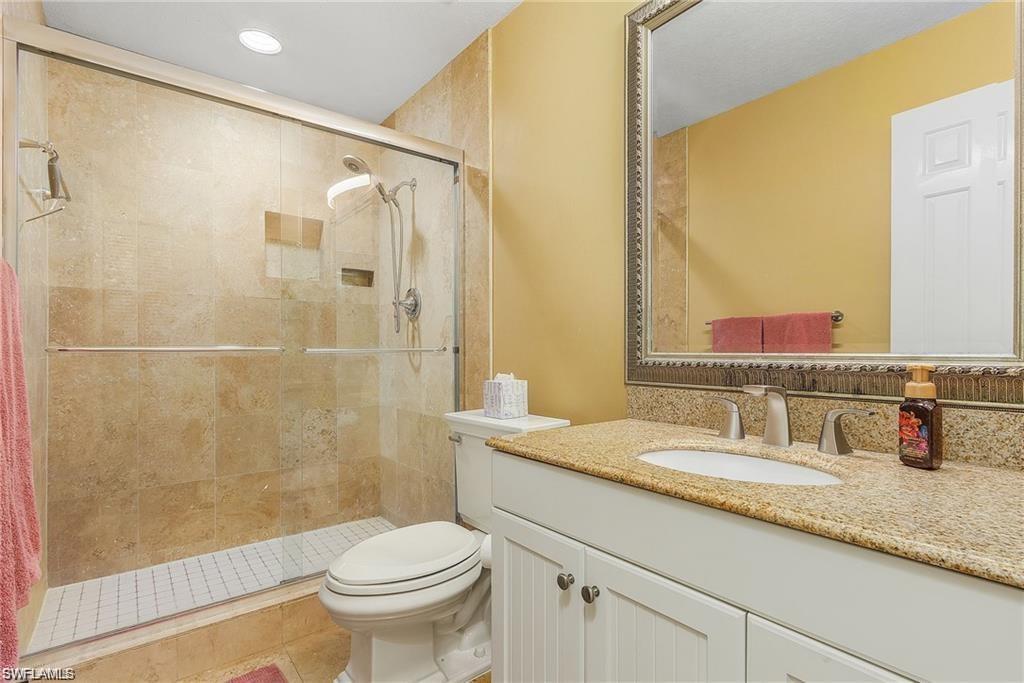 Full bath featuring toilet, a stall shower, vanity, and tile patterned flooring