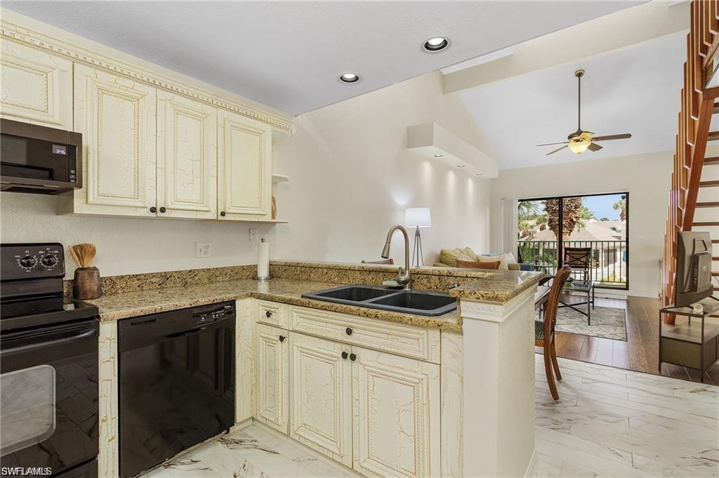 Kitchen featuring a peninsula, vaulted ceiling with beams, a sink, black appliances, and cream cabinets