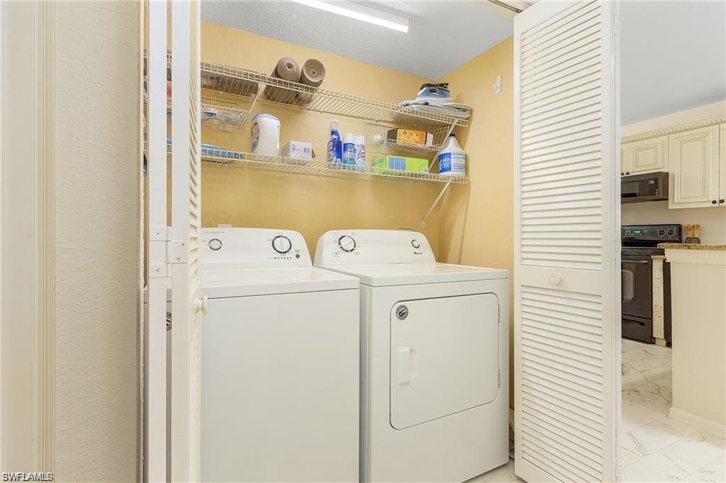 Laundry room with washer and dryer, laundry area, and marble finish floor