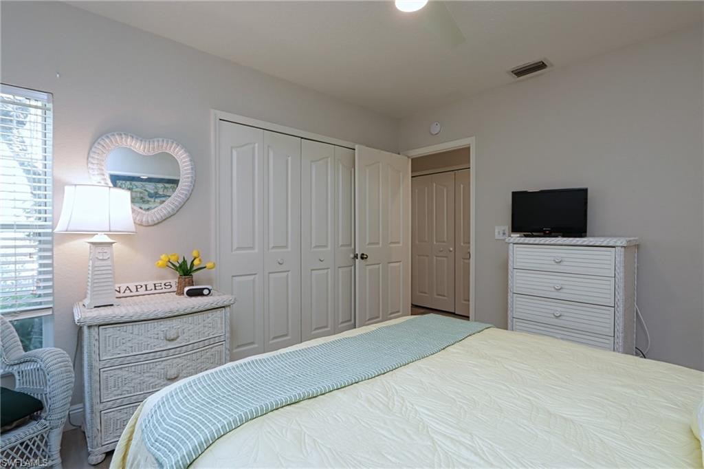 Bedroom with ceiling fan, multiple windows, and two closets