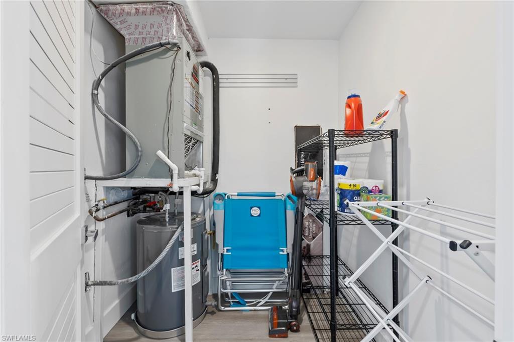 Utility area featuring a water heater, furnace system, and wood-finish flooring