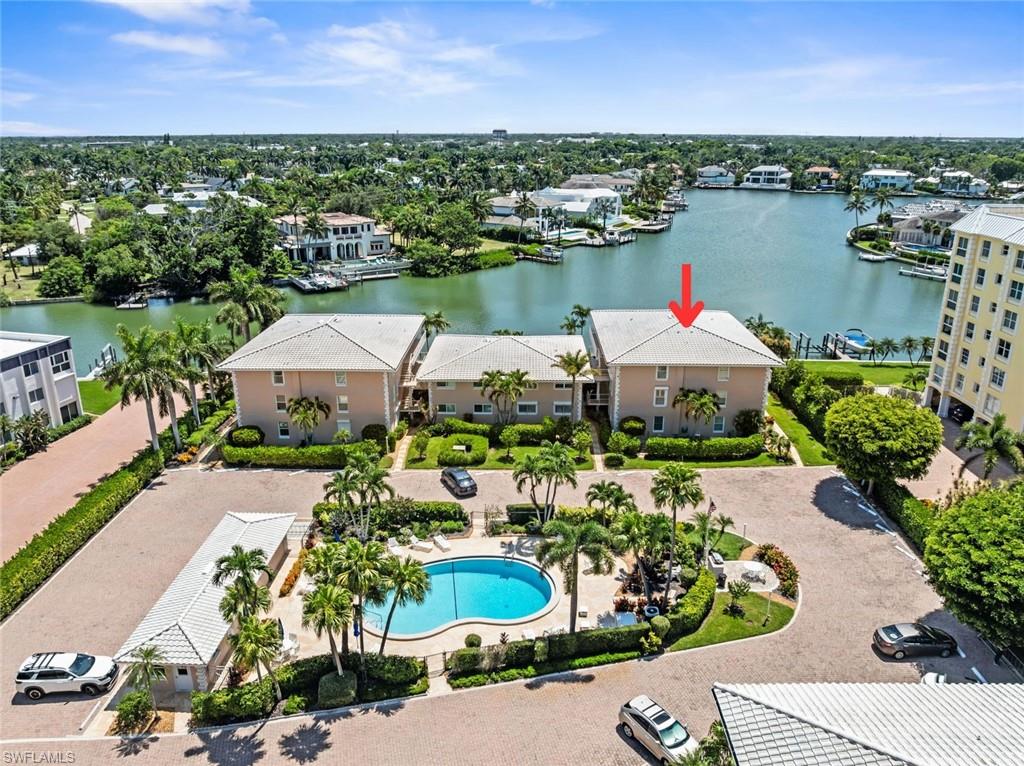 Aerial perspective of a multi-story residential building with a gabled roof, situated waterfront