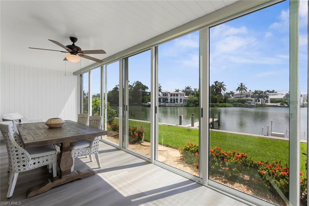Expansive sunroom featuring full-height sliding glass panels, light wood-finish flooring, and a ceiling fan with integrated lighting