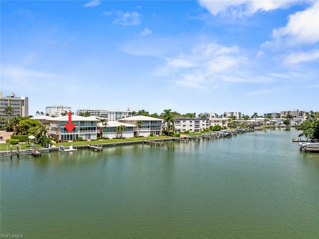 Waterfront property featuring a private boat dock, manicured lawn, and mature palm trees