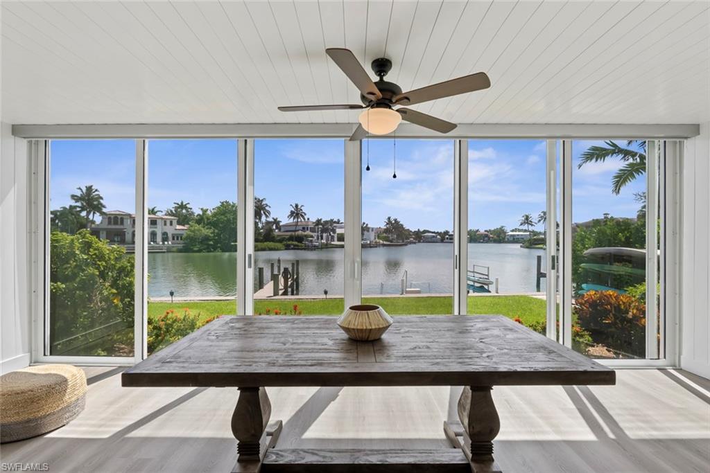 Expansive floor-to-ceiling sliding glass doors opening to a waterfront setting