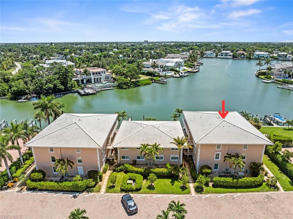 Waterfront property featuring three structures with tile roofs and stucco exteriors