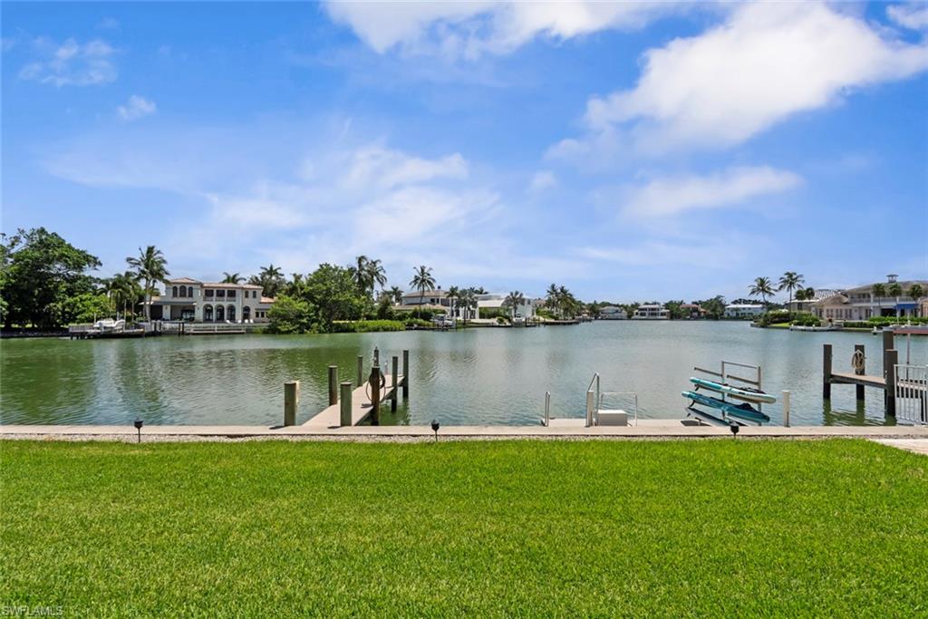 Grassed lawn area with a concrete seawall, a wooden dock with pilings, and waterway access