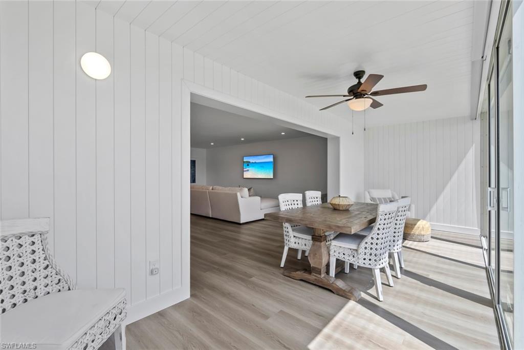 Light wood-finish flooring extending into an interior space with white vertical paneling