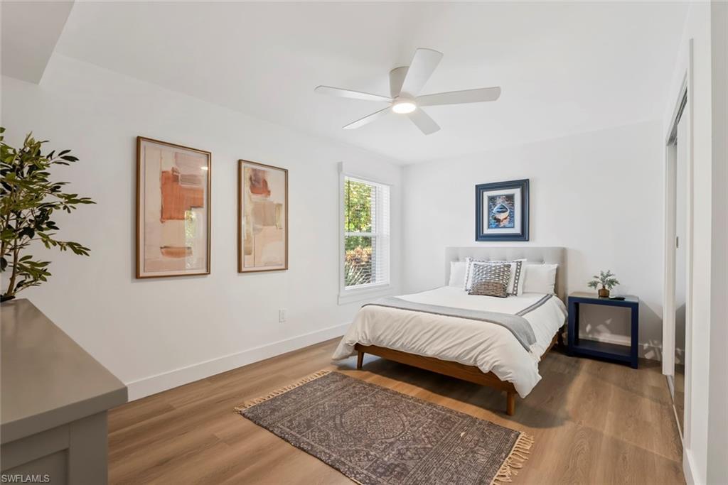 Bright room featuring a ceiling fan with integrated lighting, wood-finish flooring, white baseboards, and a window with natural light