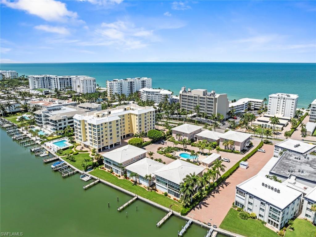 Waterfront property featuring multiple boat docks, a large swimming pool, and mature palm trees