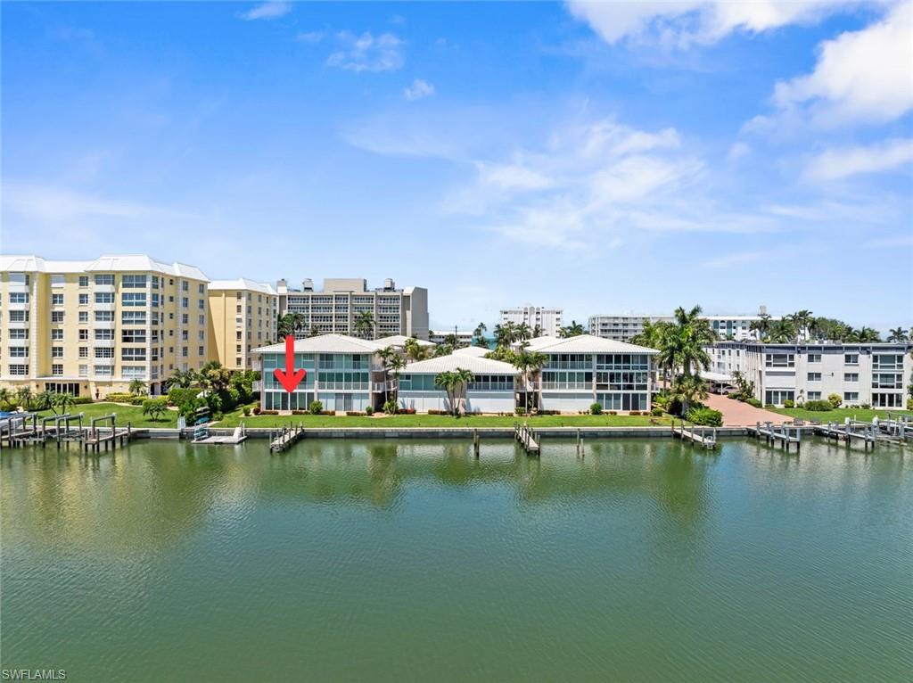 Waterfront multi-story building featuring a dock and multiple slips