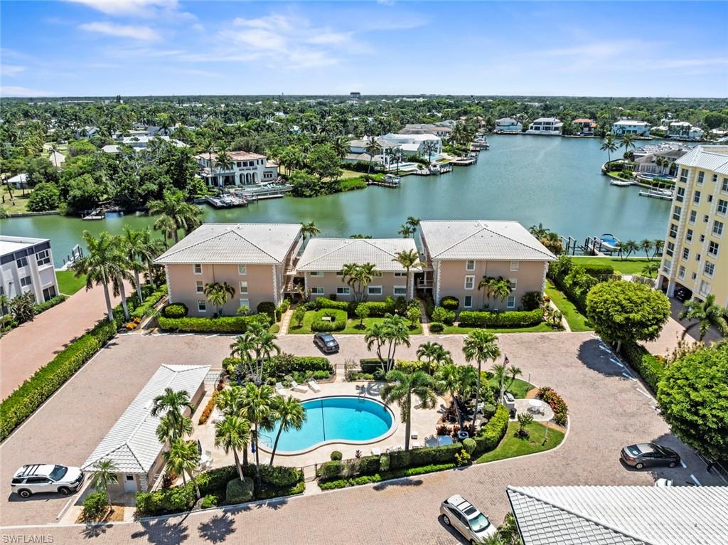 Expansive outdoor common area featuring a central swimming pool with surrounding patio, mature palm trees, and lush landscaping