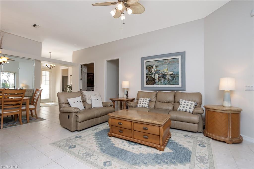 Living room with light tile patterned floors, ceiling fan, and a chandelier