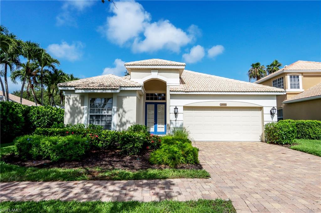 Mediterranean / spanish house with stucco siding, a garage, a tile roof, and driveway