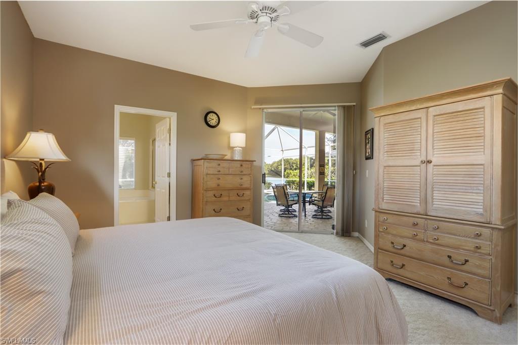 Bedroom featuring light colored carpet, access to outside, ensuite bath, and a ceiling fan