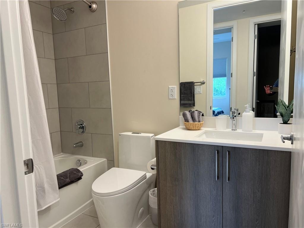 Full bathroom with tile patterned floors, shower / tub combo with curtain, vanity, and toilet