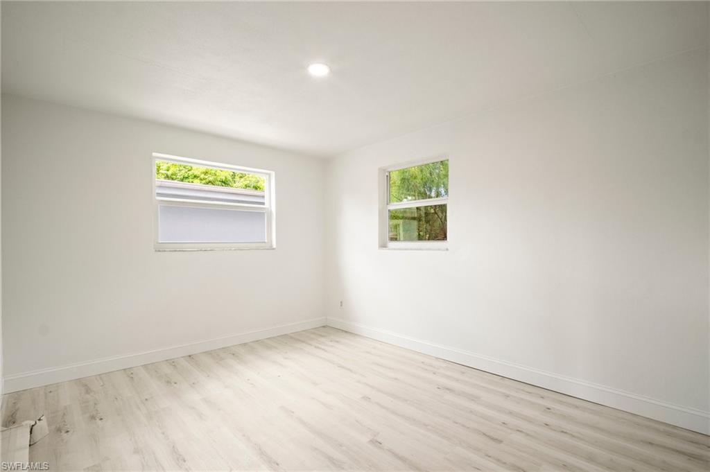 Unfurnished room featuring wood finished floors, plenty of natural light, and recessed lighting