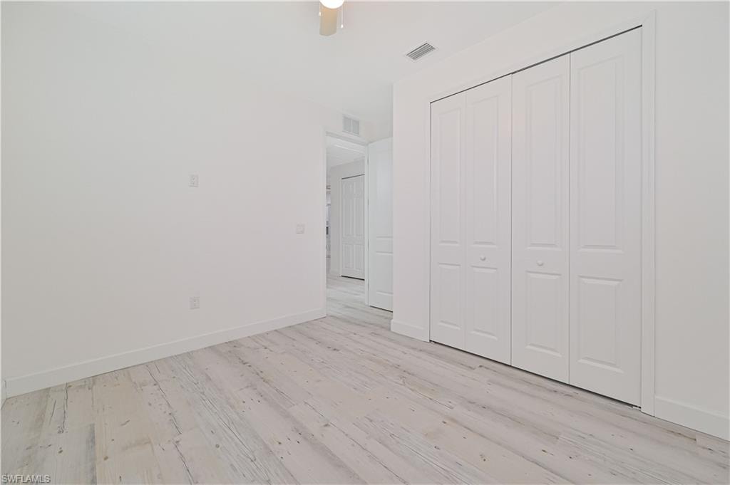 Unfurnished bedroom with light wood-type flooring, ceiling fan, and a closet