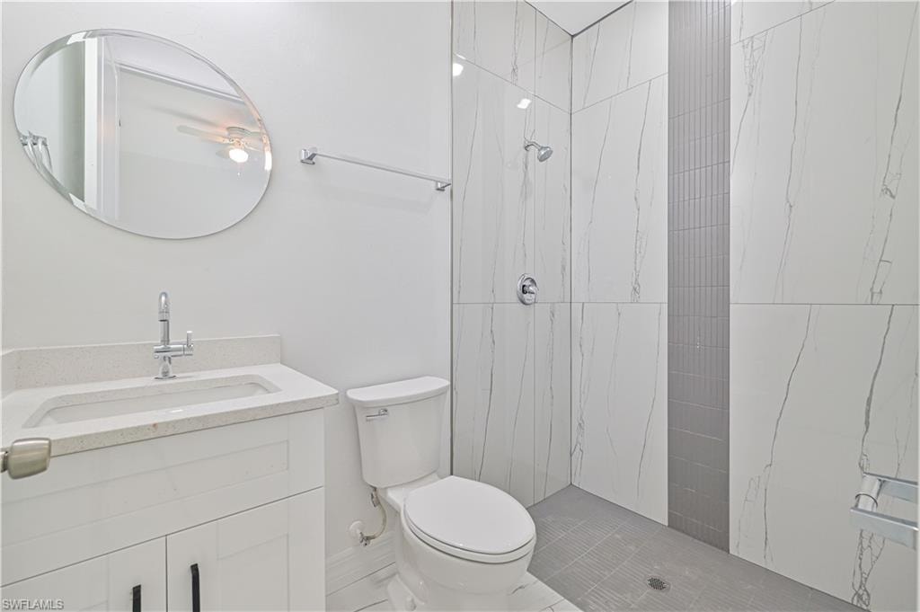 Bathroom with tiled shower, vanity, and toilet