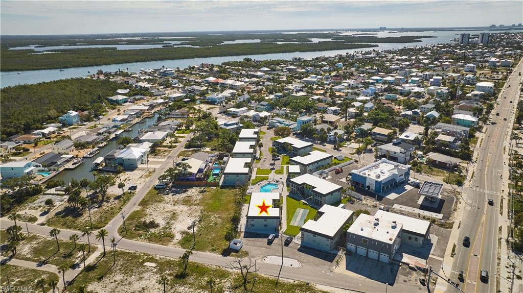Aerial perspective showcasing a coastal community with multiple residential structures, a waterway with boat access, and a prominent road
