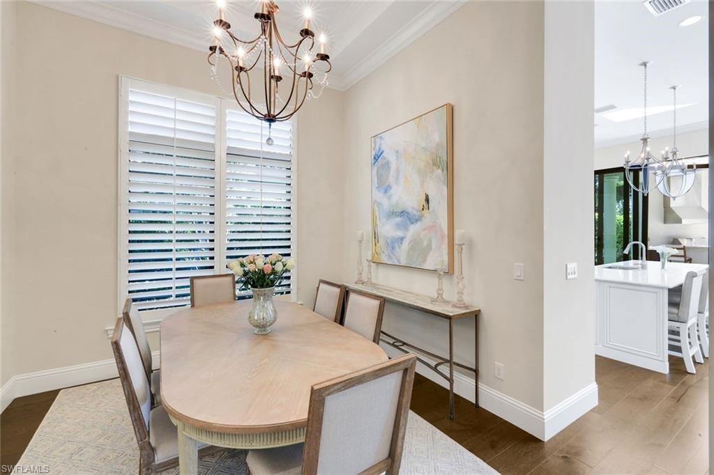 Dining room with a chandelier, wood finished floors, and crown molding
