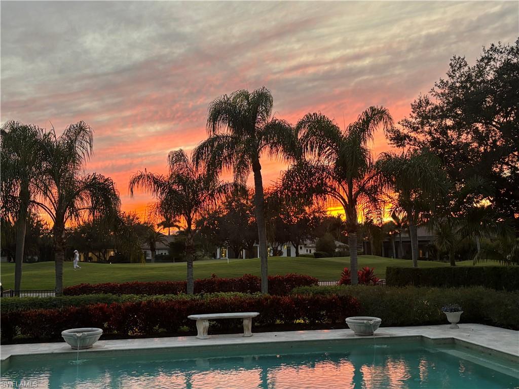 Pool at dusk featuring an outdoor pool, a patio area, and a lawn
