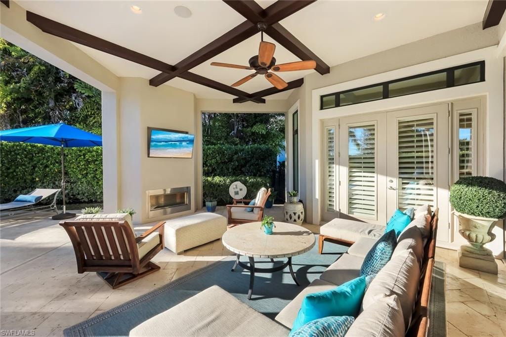 View of patio with an outdoor living space with a fireplace, a ceiling fan, and french doors