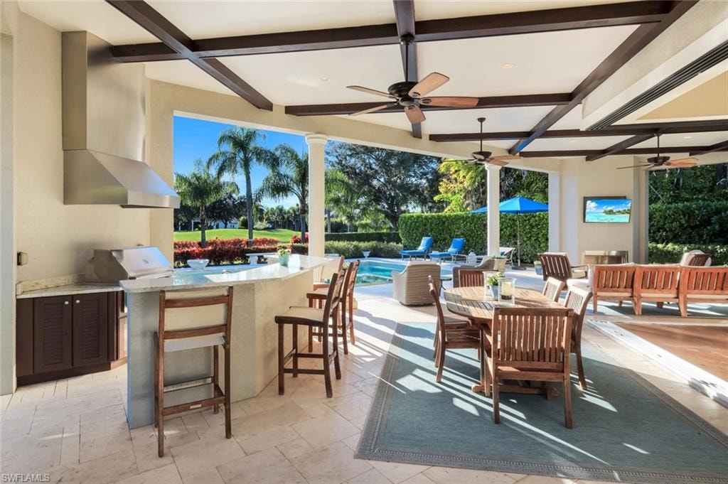 View of patio featuring outdoor dining space, an outdoor kitchen, ceiling fan, and an outdoor pool
