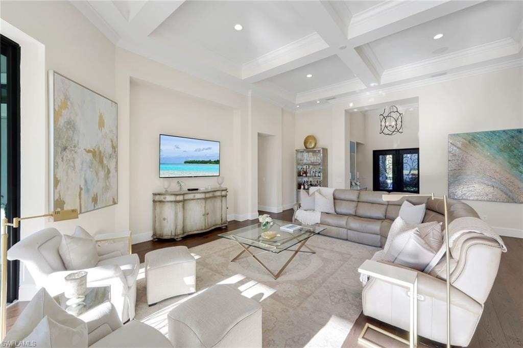 Living area with a towering ceiling, coffered ceiling, beam ceiling, wood finished floors, and crown molding throughout