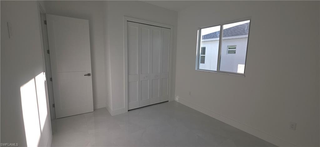 Bright interior room featuring light-toned flooring, white walls, and a modern bi-fold closet door