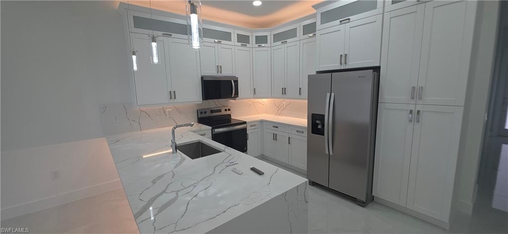 Kitchen featuring an expansive island with a waterfall-edge countertop, an undermount sink, and a high-arc faucet