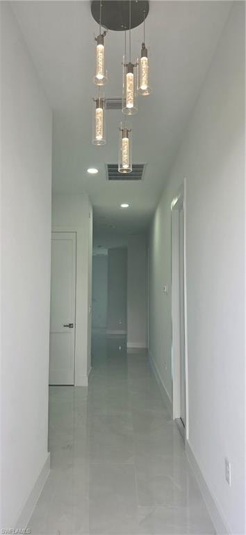 Contemporary hallway featuring a multi-light pendant fixture, recessed lighting, and light-toned tile flooring