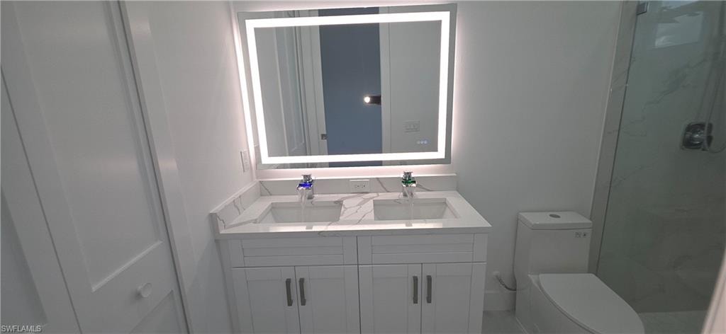 Dual vanity with stone-finish countertop, integrated sinks, and backlit mirror