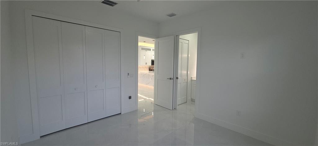 White bi-fold closet doors with panel detailing, glossy tile flooring, and white painted walls