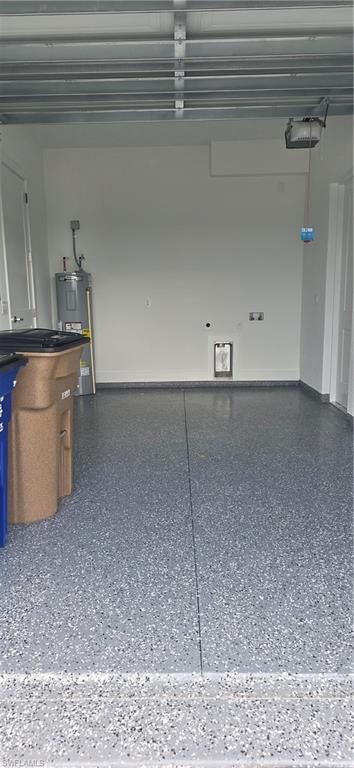 Garage interior featuring a speckled epoxy floor coating, exposed ceiling joists, and a wall-mounted water heater