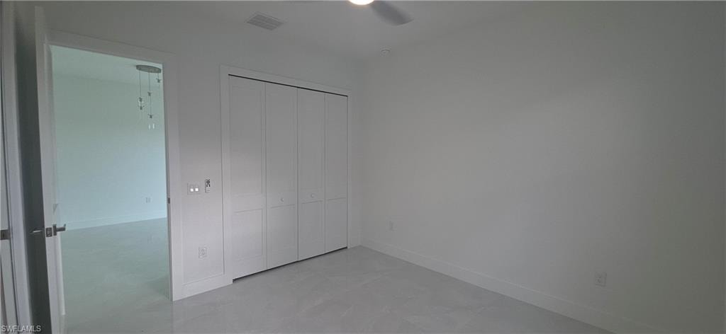Bright room featuring a ceiling fan, light-colored floor tile, and a double bi-fold closet