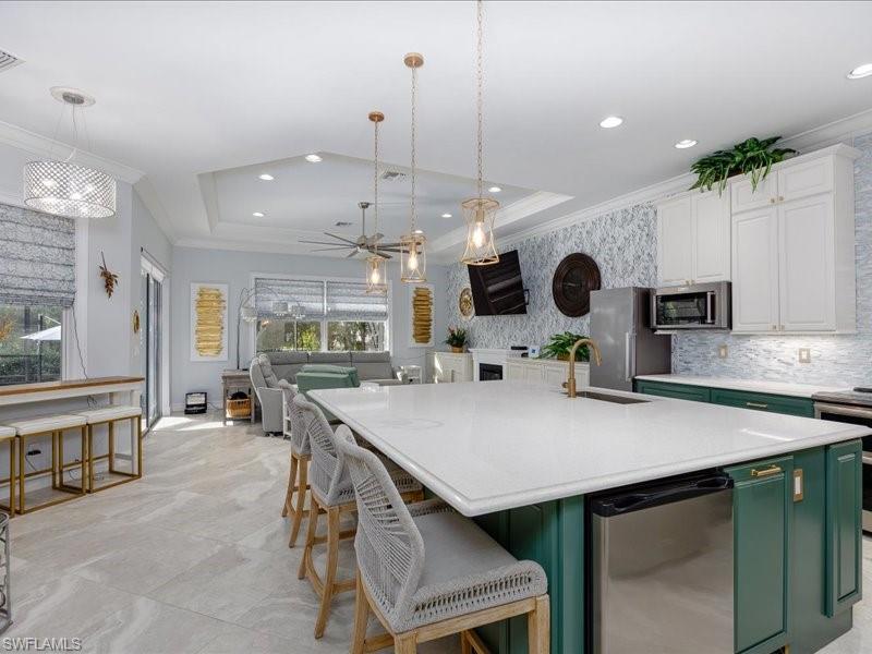 Spacious open-concept living area featuring a kitchen island with stone countertop, stainless steel undercounter refrigerator, and pendant lighting