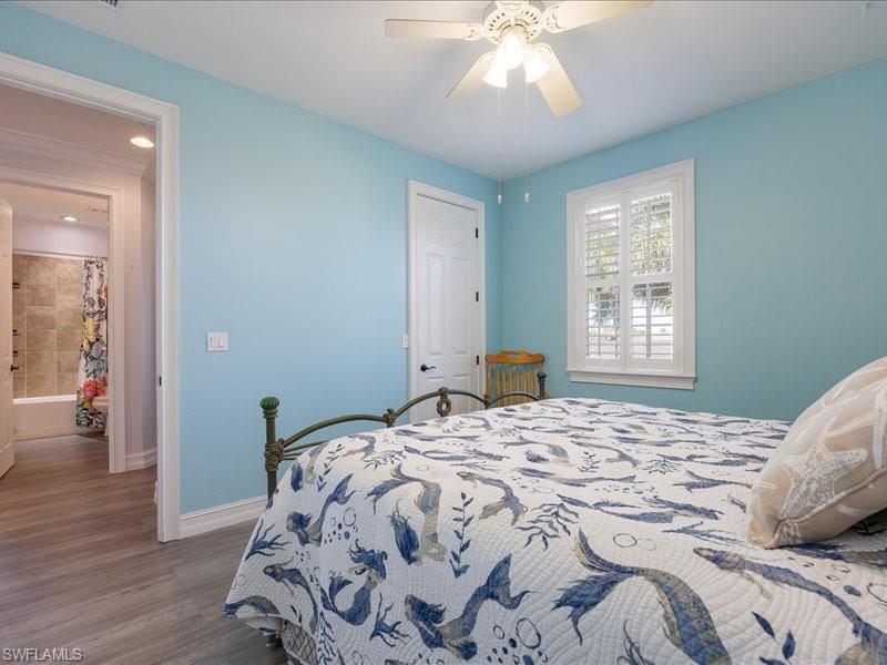Bedroom featuring light blue walls, wood-finish flooring, and a ceiling fan with integrated lighting