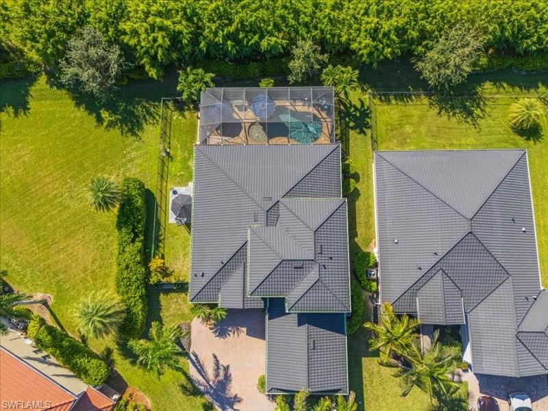 Expansive property featuring a screened-in pool, lush green lawn, mature landscaping, and a multi-gabled roofline