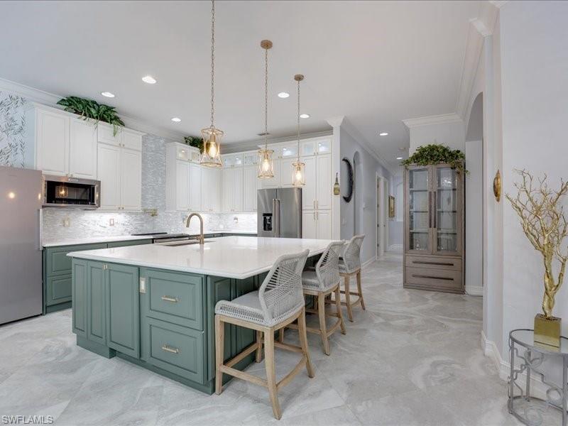 Gourmet kitchen featuring a large central island with seating, white shaker cabinetry, a mosaic tile backsplash, stainless steel appliances, and wood-finish flooring