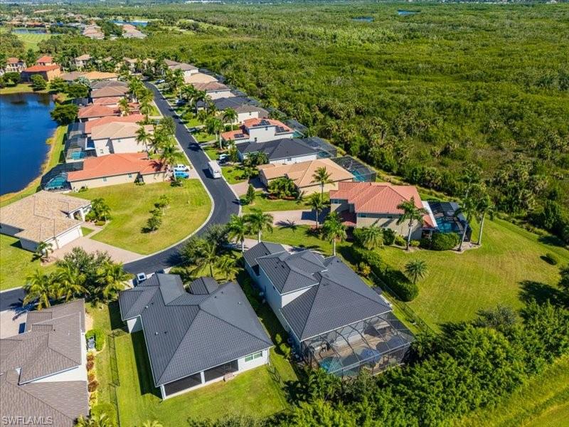 Aerial view of a residential community featuring a curved paved road and a substantial natural green space