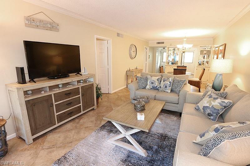 Living room with a chandelier, light tile floors, and crown molding